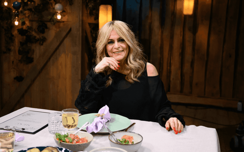 Laulaja istuu Vain elämää -pöydässä ja hymyilee kameralle. Kuva: 2025.