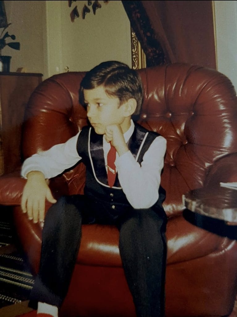 Nuori dimitri keiski istumassa juhlavaatteissa kotona