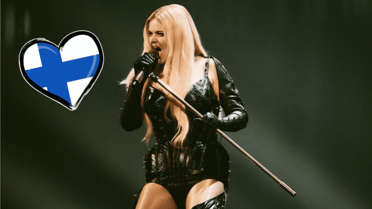 Erika Vikman esiintyy lavalla näyttävässä mustassa esiintymisasussa, taustalla sinivalkoinen sydänsymboli.