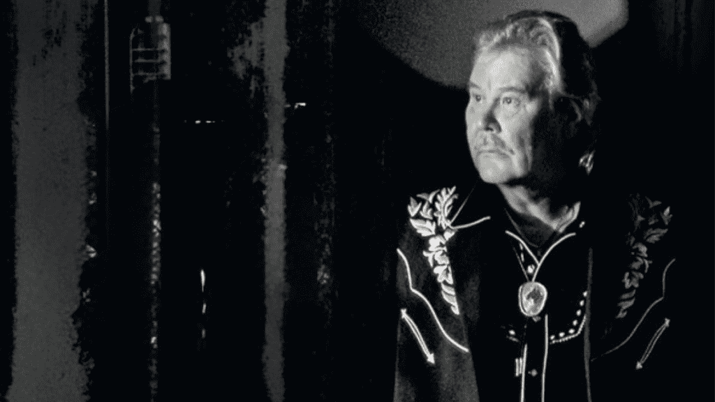 Mustavalkoinen kuva Kulkuriveli Jami Hemmosta, joka katsoo sivulle esiintymisasussaan.