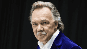 Laulaja poseeraa studiossa tummassa taustassa, yllään sininen samettitakki.