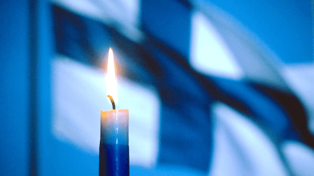 itsenäisyyspäivän sinivalkoinen kynttilä ja Suomen lippu – suomalaisuuden symbolit.