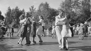 Historiallinen kuva suomalaisista tanssimassa ulkotanssilavalla kesäpäivänä.