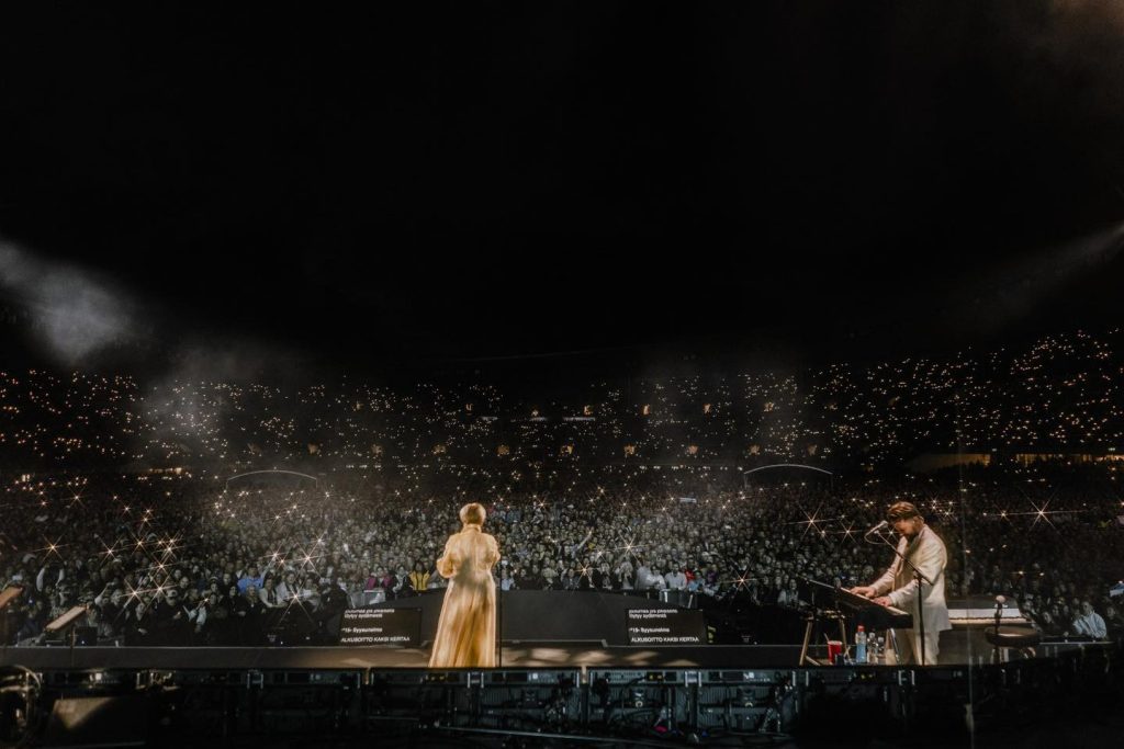 Laaja näkymä helsingin olympiastadionin yleisöstä ja lavasta katri helenan uran päätöskonsertissa yleisössä tuhansia valoja