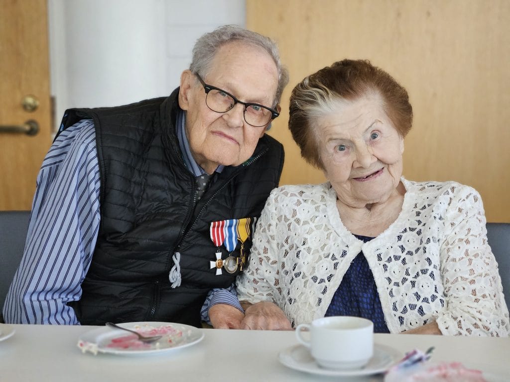 Kihloihin menneet Matti Hara ja Senni Sopanen poseeraavat hymyillen vierekkäin kahvilla